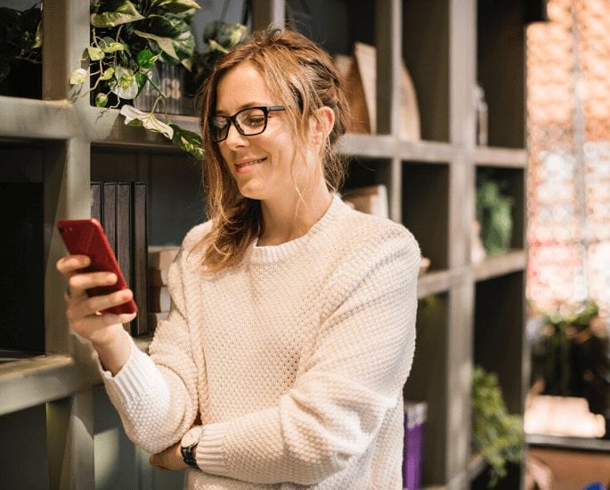 Woman with glasses using HSSCU Online Banking on a phone.