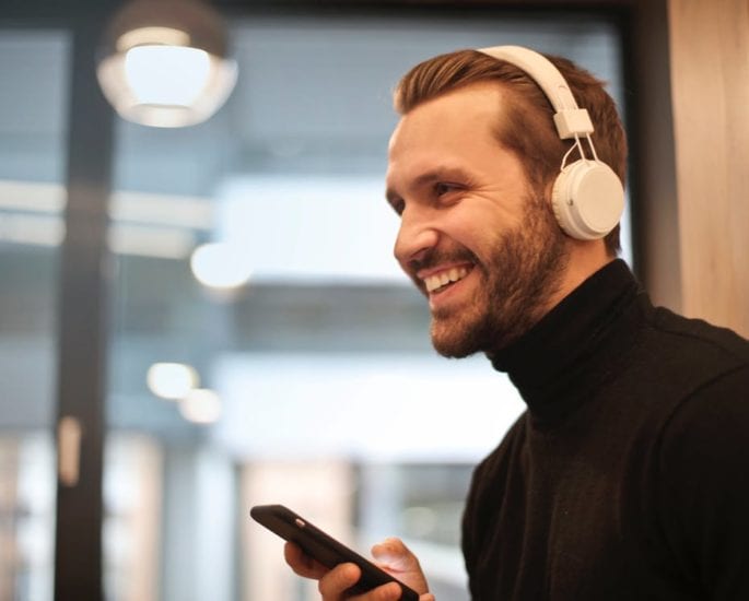 Man with white headphones using his mobile phone.