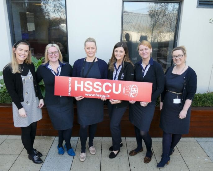 HSSCU staff members holding a HSSCU sign at our offices.